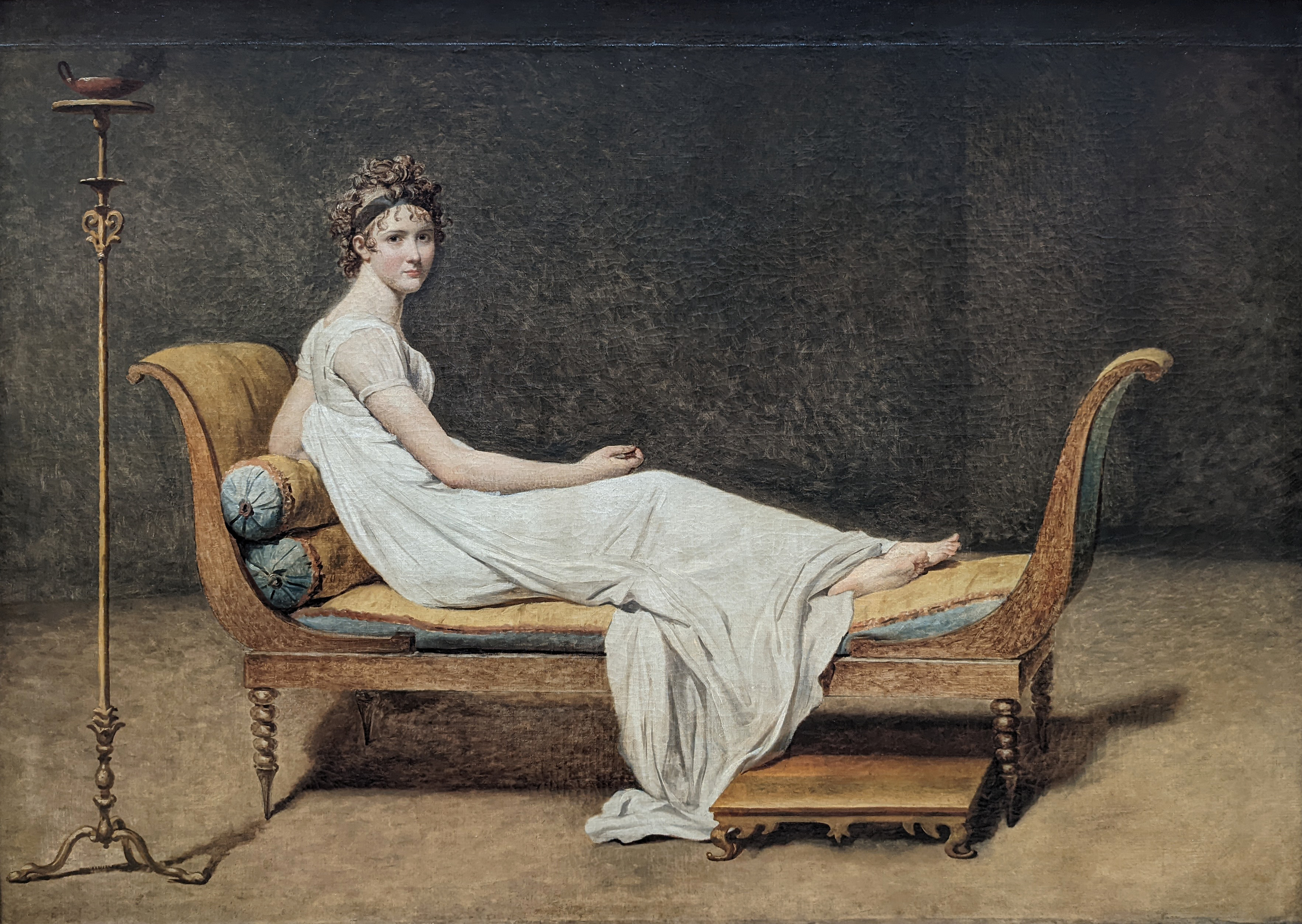 Jacques-Louis David, <em>Juliette Récamier</em>, olio su tela, 1800, Parigi, Musée du Louvre.
<br>Immagine in pubblico dominio. Fonte: <a href=https://commons.wikimedia.org/wiki/File:Madame_R%C3%A9camier,_n%C3%A9e_Julie_(dite_Juliette)_Bernard_-_Jacques-Louis_David_-_Mus%C3%A9e_duLouvre_Peintures_INV_3708.jpg?uselang=fr#Conditions%20d%E2%80%99utilisation>Wikimedia Commons</a>.